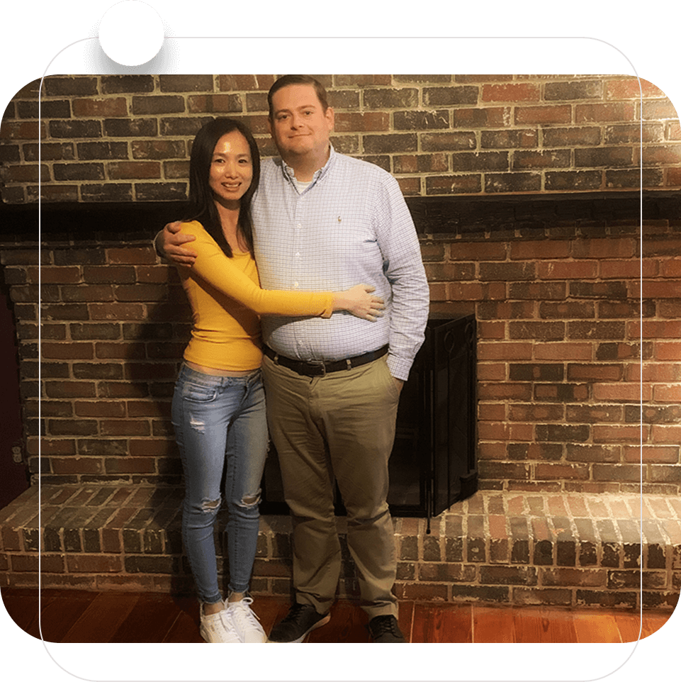 A man and woman standing in front of a fireplace.