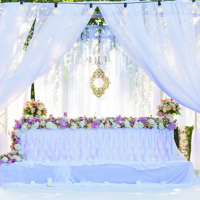 A wedding ceremony with white drapes and flowers.