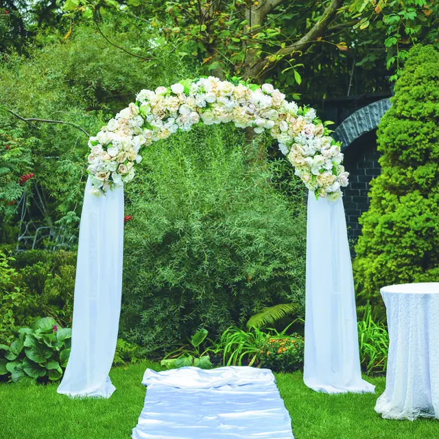 A wedding arch with white flowers and white drapes.